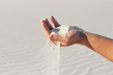 sand through your fingers, white sand pours through your fingers against the background of sand on...