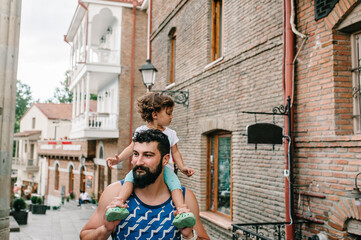 Young father walking with little daughter outdoors, on streets in city of Tbilisi in the capital of...