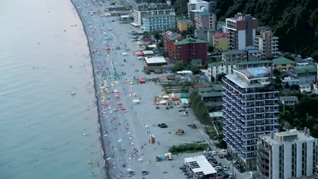 Top view of the coast of a seaside resort in the high tourist season. People relax and sunbathe on the beach in Kvariati and Gonio in Adjara.