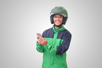 Portrait of Asian online taxi driver wearing green jacket and helmet holding a mobile phone and smiling. Advertising concept. Isolated image on white background