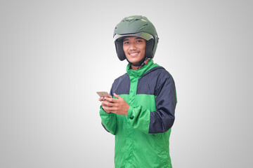 Portrait of Asian online taxi driver wearing green jacket and helmet holding a mobile phone and smiling. Advertising concept. Isolated image on white background