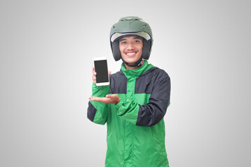 Portrait of Asian online taxi driver wearing green jacket and helmet showing and presenting blank screen mobile phone. Advertising concept. Isolated image on white background