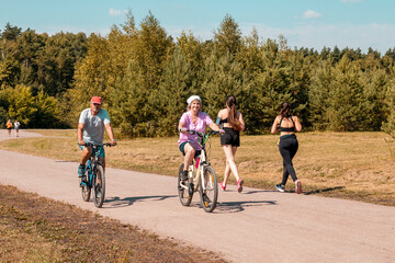 An old man and a woman are engaged in active cycling in the park. Healthy lifestyle .