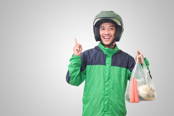 Portrait of Asian online taxi driver wearing green jacket and helmet delivering the vegetables from traditional market. Isolated image on white background