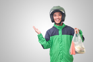 Portrait of Asian online taxi driver wearing green jacket and helmet delivering the vegetables from traditional market. Isolated image on white background
