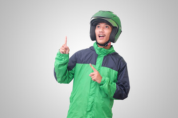 Portrait of Asian online taxi driver wearing green jacket and helmet pointing at empty space with finger. Isolated image on white background