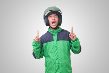 Portrait of Asian online taxi driver wearing green jacket and helmet pointing at empty space with finger. Isolated image on white background