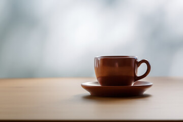 A cup of coffee is on the table near the window. Sunlight, coffee mood.