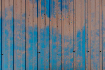 Partially painted metal fence sheet rusted in places where paint has fallen off