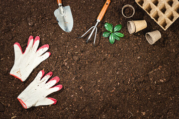 Gardening tools on fertile soil texture background seen from above, top view. Gardening or planting concept. Working in the spring garden. Flat lay mockup with border composition