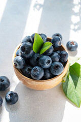 Blueberries berry in wooden bowl, on bright background. Healthy food template, mockup with copy space.