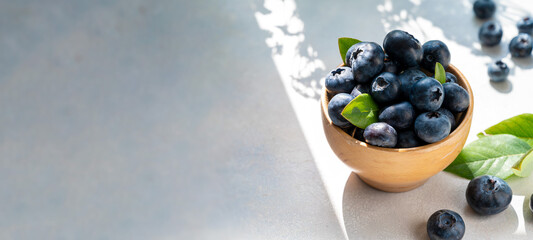 Blueberries banner, berry in wooden bowl, on bright background. Healthy food template, mockup with copy space.