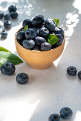 Blueberries berry in wooden bowl, on bright background. Healthy food template, mockup with copy space.