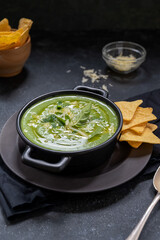 Spinach green spinach soup in black bowl. Lifestyle, moody soup served with nachos