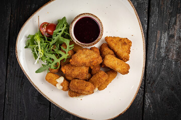 Cheese fries with herbs and sauce on plates on a wooden table
