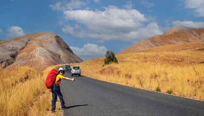 The  backpack young woman  went hitchhiking on the road around the countryside with blue sky background