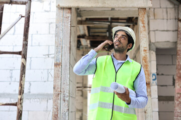 Technician civil engineer or specialist inspector discussing, brainstorm and planing real estate project work with smart mobile phone and blueprint at Industrial building site. Construction concept