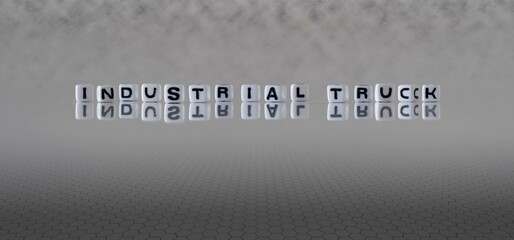 industrial truck word or concept represented by black and white letter cubes on a grey horizon...
