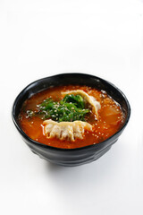 Oriental soup with dumplings and algae served in a black bowl.
Dish on a white background