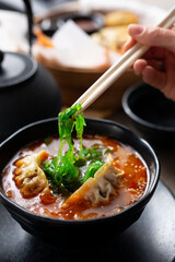 Japanese soup. The woman is eating the soup with chopsticks