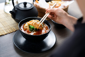 Japanese soup. The woman is eating the soup with chopsticks