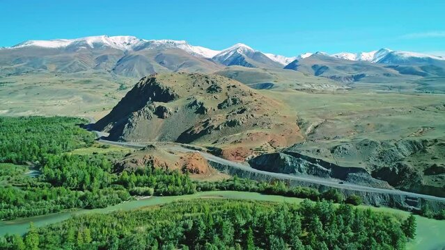 Aerial of majestic snow capped mountain range and green valley in highlands of Republic of Altai, Russia
