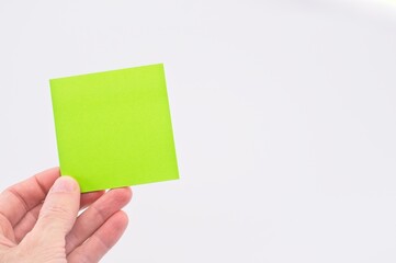mano che regge un pezzo di carta verde con spazio vuoto per messaggio su sfondo bianco