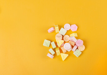Tablet candies on yellow background. Compressed sugar powder confectionery, dextrose candy necklace...