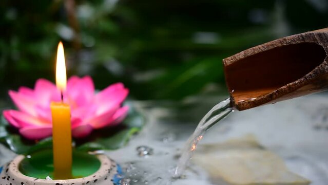 Light a candle, gutter flowing bamboo, lotus flower, spa concept.