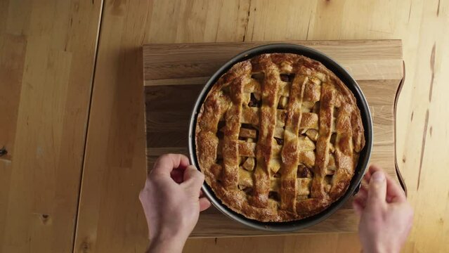 A male home chef making traditional Dutch apple pie - removing baking form from ready pie.
