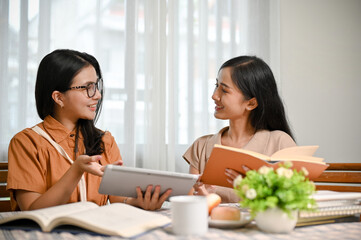 Obraz premium A beautiful Asian female college student teaches and tutors her friend in math subjects