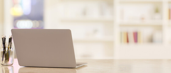 Workspace tabletop with notebook laptop and copy space over blurred office or library background.