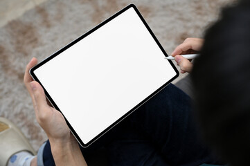 Overhead, A man relaxing in living room, using digital tablet. tablet white screen mockup.