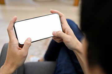 close-up, A young Asian man relaxing in living room and playing mobile game on his smartphone