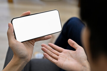 A guy watching game live-streaming on his smartphone. dissatisfaction gesture expression.