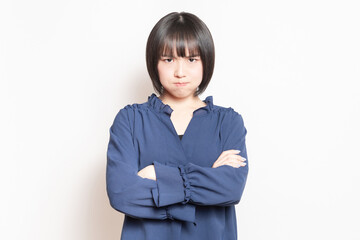 白背景の前に立って、怒っている若い女性