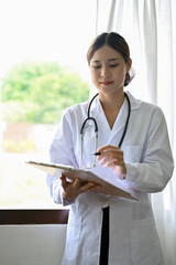 Portrait, Professional Asian female doctor holding a medical clipboard.