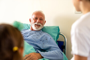 Happy recovering grandfather is visited by his grandchildren in the hospital.