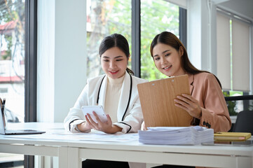 Two beautiful Asian businesswomen or female accountants working together in the office.