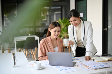 Two beautiful young Asian businesswomen working together in the office.