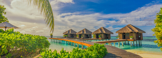 Luxury hotel with water villas and palm tree leaves over white sand, close to blue sea, seascape....