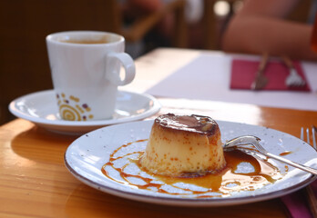  spanish flun pudding dessert closeup photo with teaspoon and cup of coffee on the background
