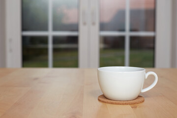 blurred background of kitchen and white cup of tea