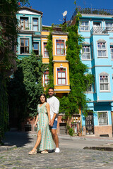 Young couple in love on an Istanbul street embracing and in the background colorful buildings with...
