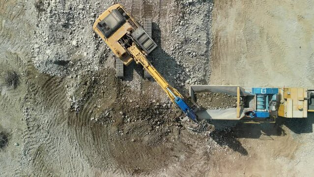 Construction excavator works at the industrial quarry that loads earth, sand and stones.