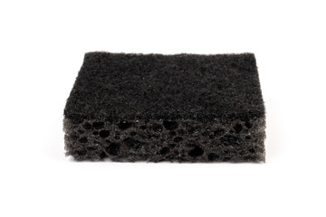 Black sponge used for washing dishes. Has two surfaces which are rough and smooth.