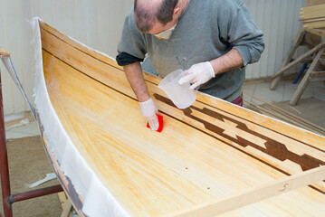Young carpenter making wooden boat of his own design in his workshop