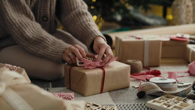 Unrecognizable caucasian woman wrapping Christmas gifts on the floor. Shot with RED helium camera in 8K.   