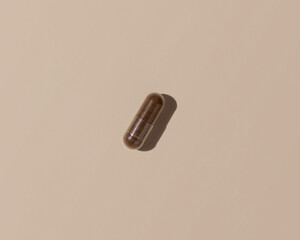 Brown Medical capsule on light beige top view, hard shadows. Taking dietary supplements