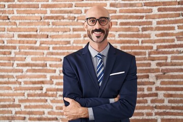 Bald man with beard wearing business clothes and glasses happy face smiling with crossed arms looking at the camera. positive person.